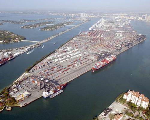 Arial photo of the Port of Miami with large number of cargo containers, container ship and barge.